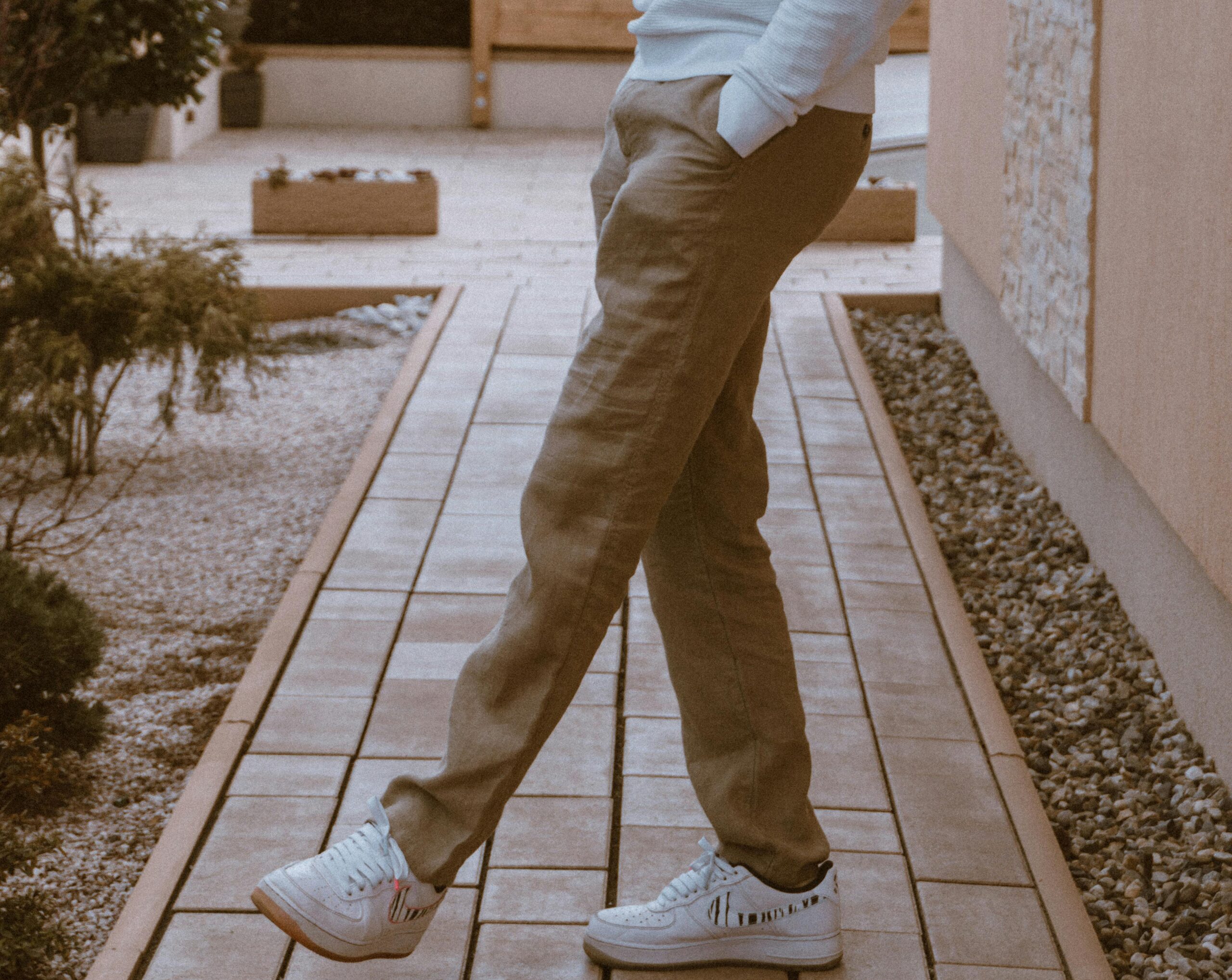 Person wearing beige chinos and white sneakers walking on a tiled path